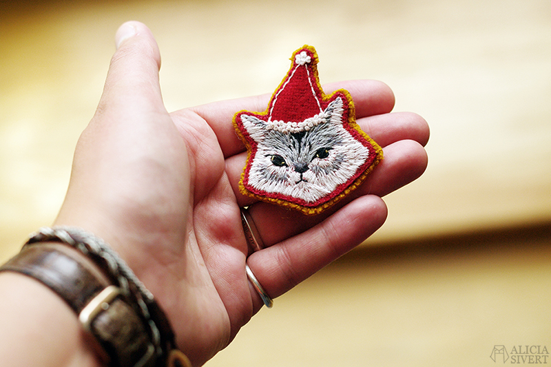 Lussekatt, broderad brosch av katt i tomteluva, av Alicia Sivertsson. / Embroidered Christmas cat brooch by Alicia Sivertsson. aliciasivert alicia sivert sivertsson broderi broderier embroidery hand needlework fritt skapa skapande kreativitet konst textil textilkonst schattérsöm broderad brosch embroidered brooch christmas cat julkatt jul katt tomteluva lussekatt