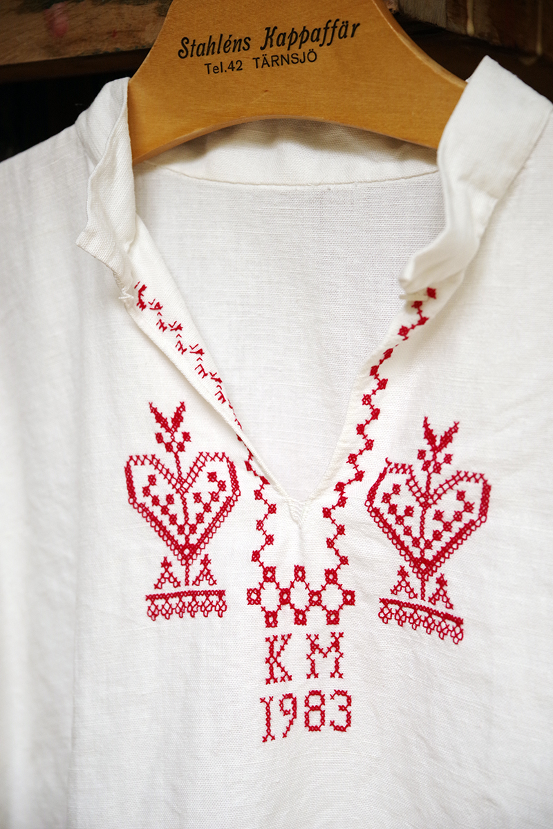 Vit linneskjorta med broderade detaljer i röda korsstygn runt hals och ärmslut. Bokstäverna KM och året 1983. Loppisfynd i Karin Larssons anda - www.aliciasivert.se