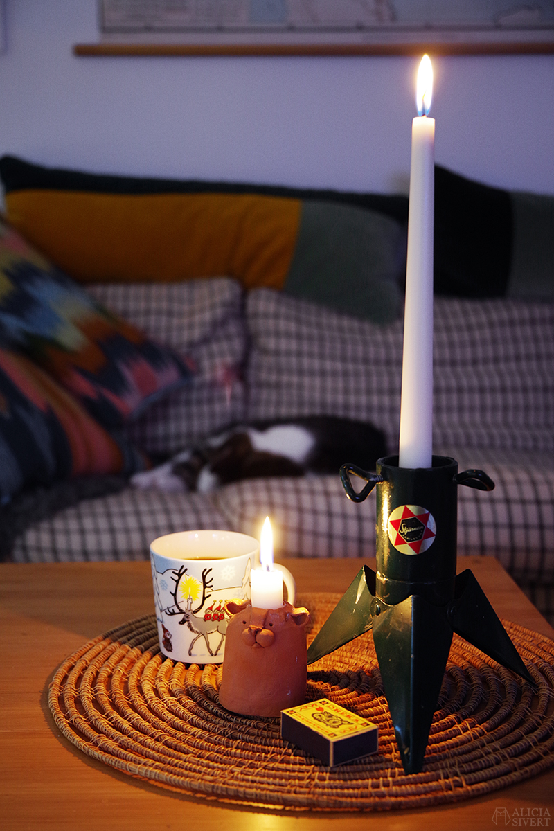 Ljusstake av en liten julgransfot och en muckla i keramik av Andrea Grath. En katt sover i soffan i bakgrunden.