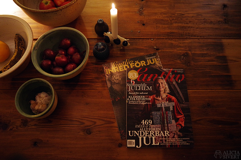 Foto ovanifrån av Lantlivs julmagasin invid ett tänt ljus.