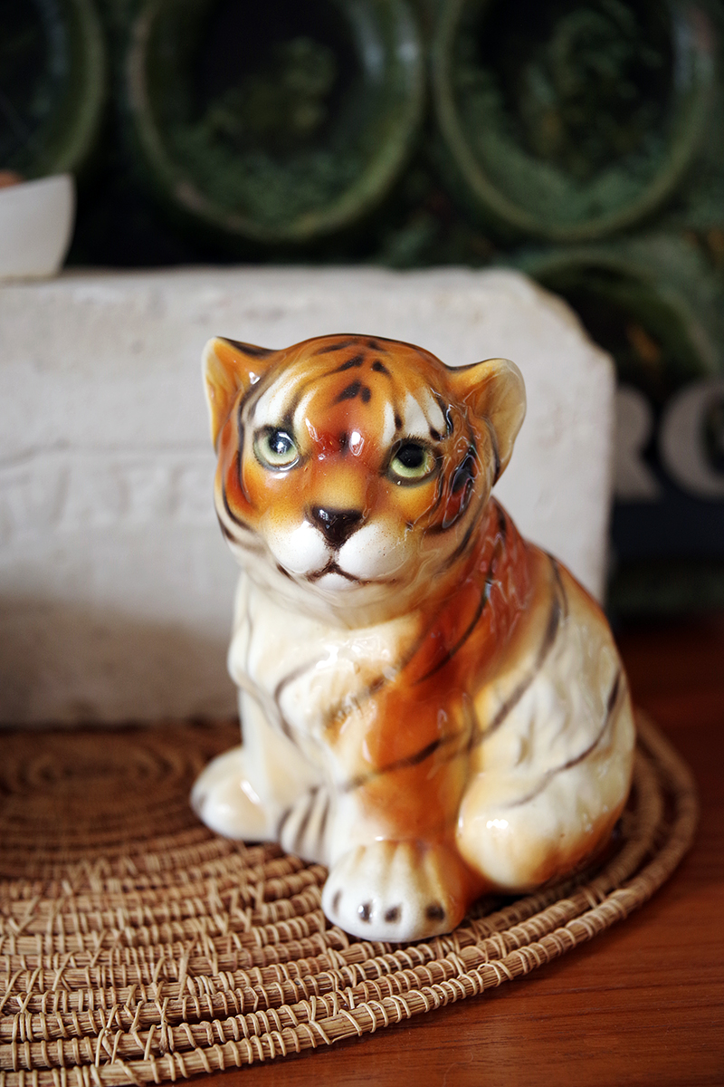 En porslinsfigur i form av en tiger som tittar under lugg.